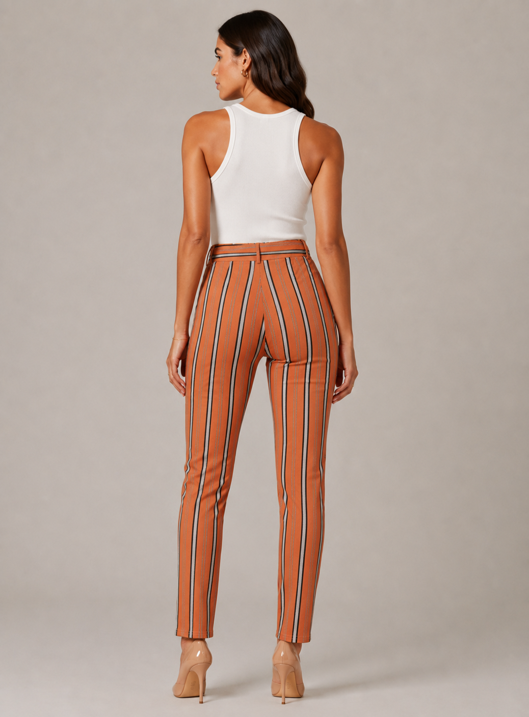 Women's high-waisted belted trousers in terracotta with vertical black, white, and grey stripes, featuring a tie-front waist and slim fit.