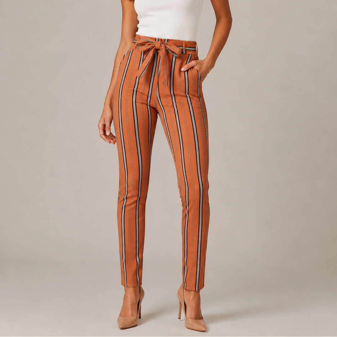 Women's high-waisted belted trousers in terracotta with vertical black, white, and grey stripes, featuring a tie-front waist and slim fit.