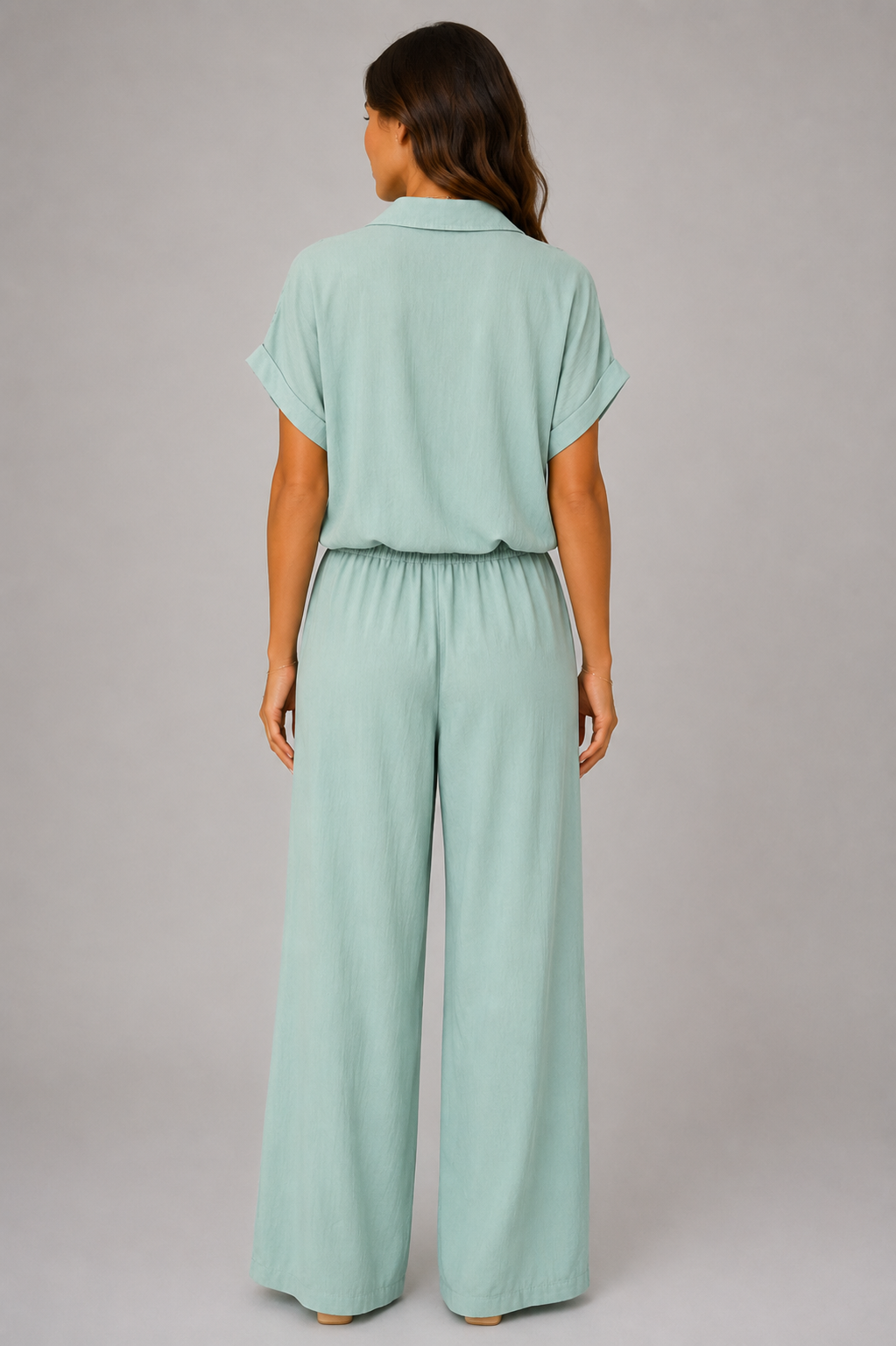Woman modelling a Made in Italy two-piece lounge set in a soft textured fabric. The outfit features a relaxed short-sleeve collared shirt with button-front detail and a tie-front hem, paired with wide-leg elasticated waist trousers. Shown in multiple colours against a light grey studio background.