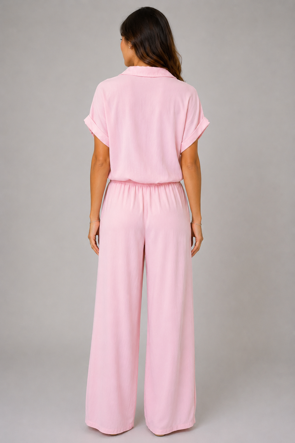 Woman modelling a Made in Italy two-piece lounge set in a soft textured fabric. The outfit features a relaxed short-sleeve collared shirt with button-front detail and a tie-front hem, paired with wide-leg elasticated waist trousers. Shown in multiple colours against a light grey studio background.