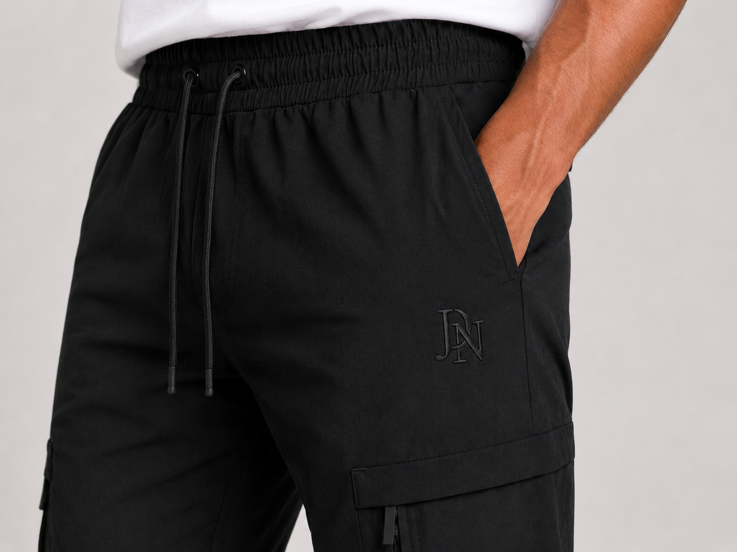 Men's slim fit black cargo trousers with side zip pocket, cuffed ankles, and elastic waistband