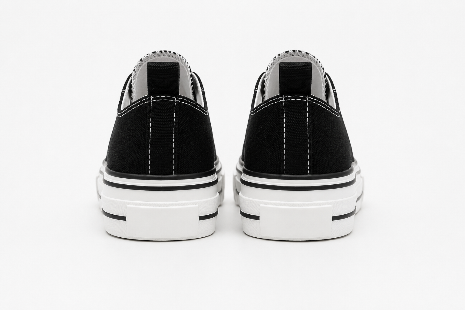 Black canvas platform trainers with white laces, white rubber toe caps and chunky white soles featuring black stripe detailing.