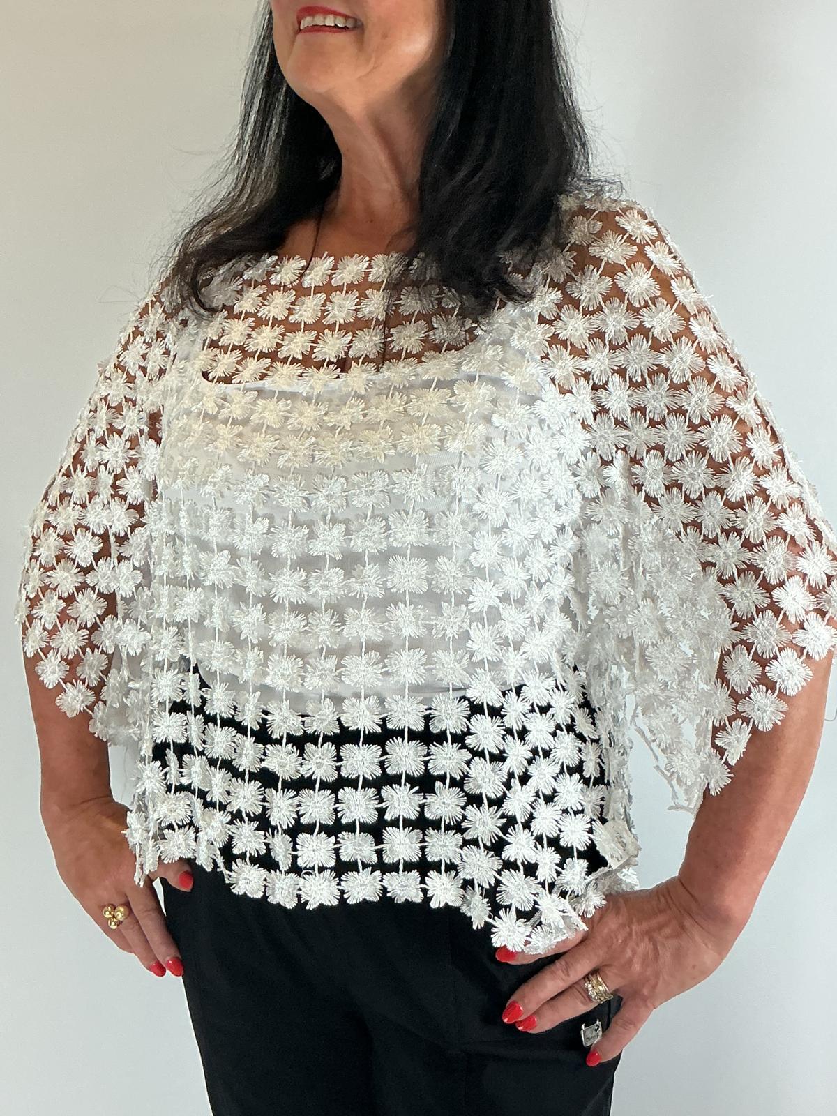 Ladies white semi-sheer floral embroidered top with short sleeves, a relaxed fit and scalloped edges