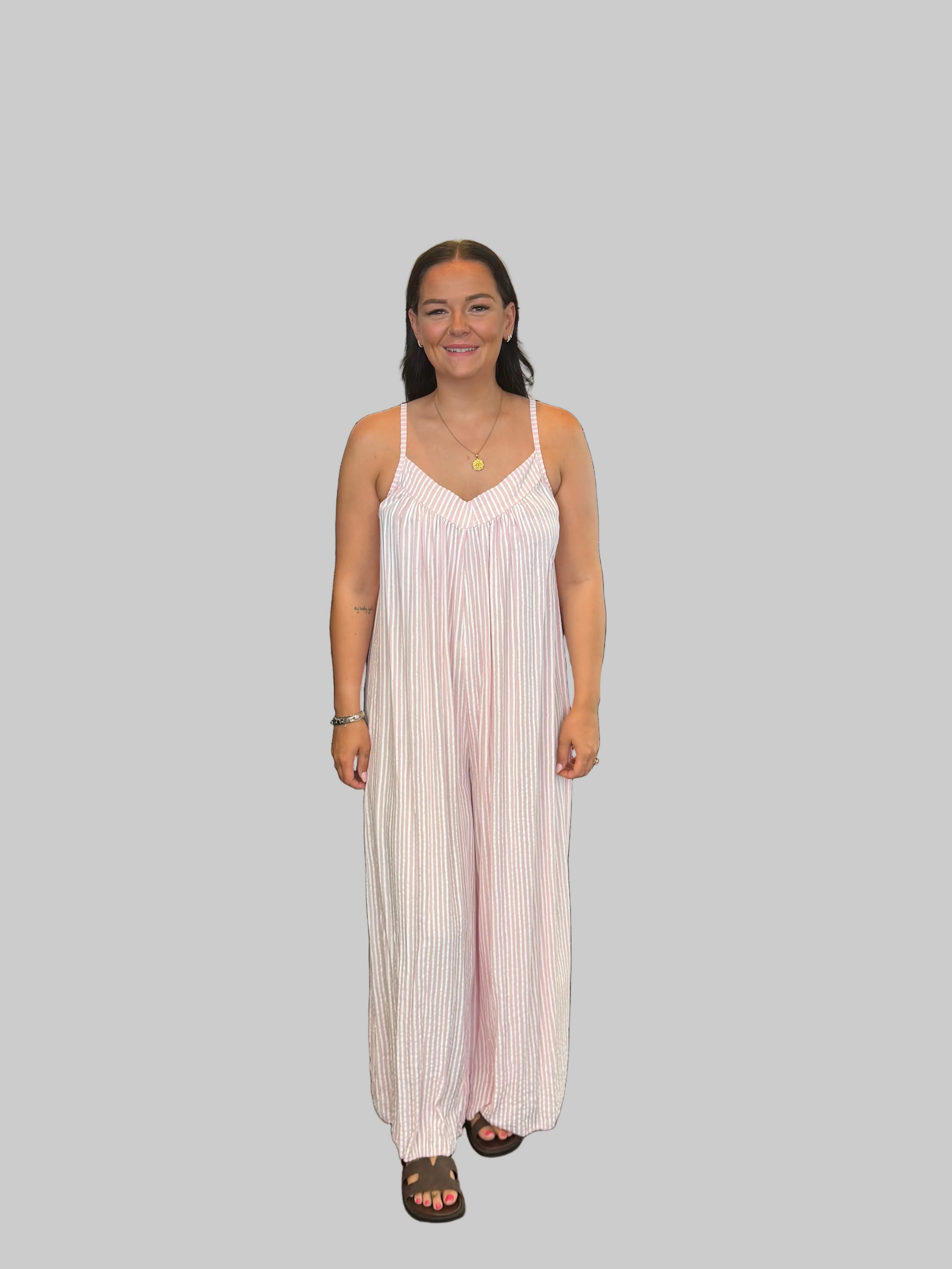 Women's Pink and white striped wide leg jumpsuit with adjustable straps, modelled with a relaxed fit