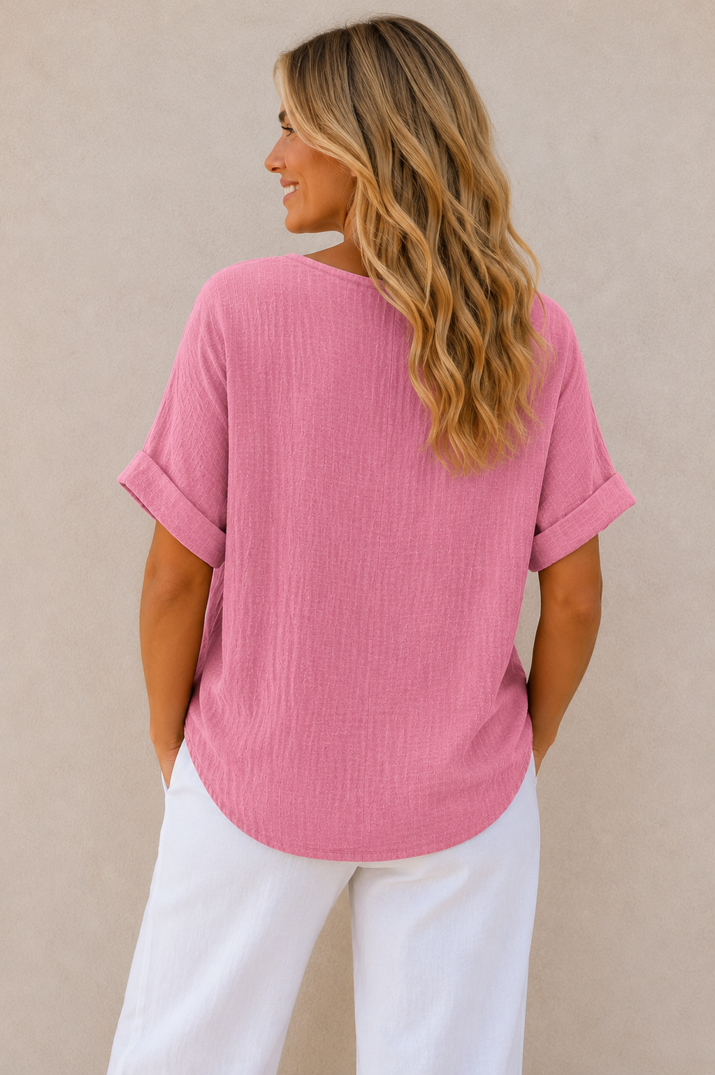 Woman wearing a relaxed-fit textured gauze top with rolled short sleeves and a scoop neckline, paired with white linen pants. Shown from both front and back views against a neutral background, highlighting the lightweight fabric, loose silhouette, and curved hem. One size fit suitable up to a size 16.