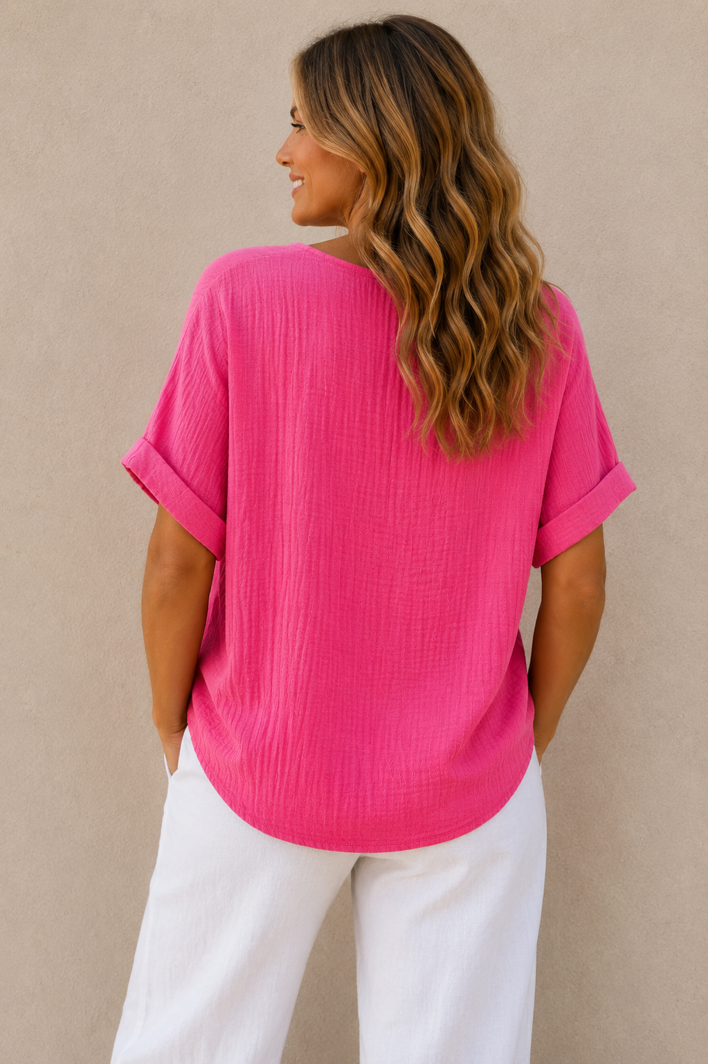 Woman wearing a relaxed-fit textured gauze top with rolled short sleeves and a scoop neckline, paired with white linen pants. Shown from both front and back views against a neutral background, highlighting the lightweight fabric, loose silhouette, and curved hem. One size fit suitable up to a size 16.
