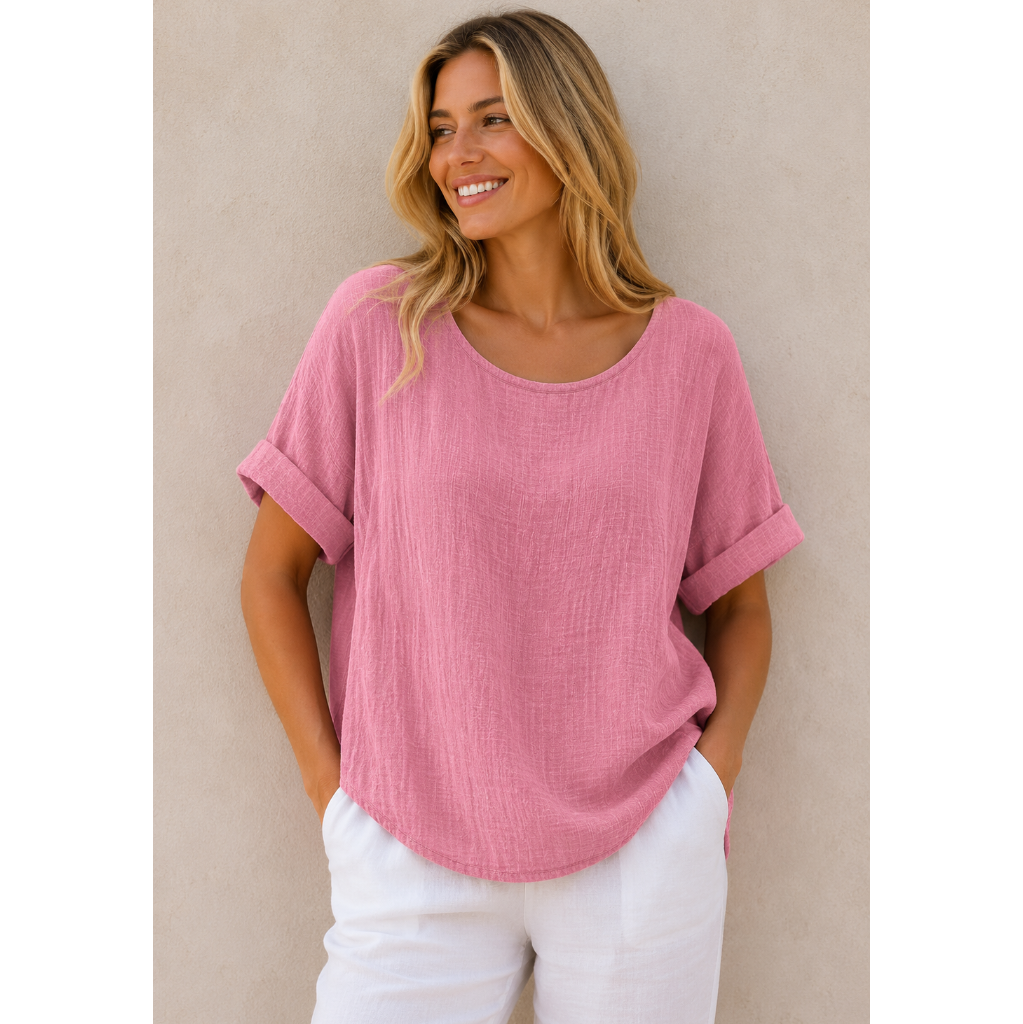 Woman wearing a relaxed-fit textured gauze top with rolled short sleeves and a scoop neckline, paired with white linen pants. Shown from both front and back views against a neutral background, highlighting the lightweight fabric, loose silhouette, and curved hem. One size fit suitable up to a size 16.