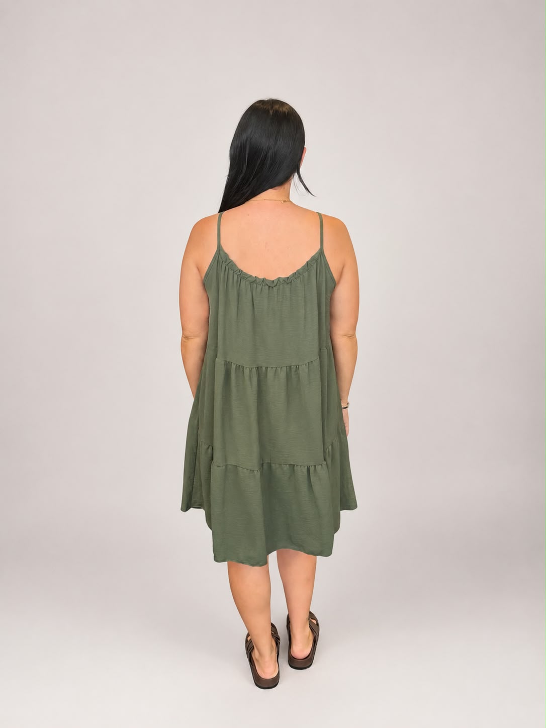 A versatile Khaki tiered cami dress featuring spaghetti straps, a relaxed, flowy fit, and a flattering knee-length design. Lightweight and easy to wear, it's ideal for casual everyday styling, holidays, weekends, and warm-weather occasions.