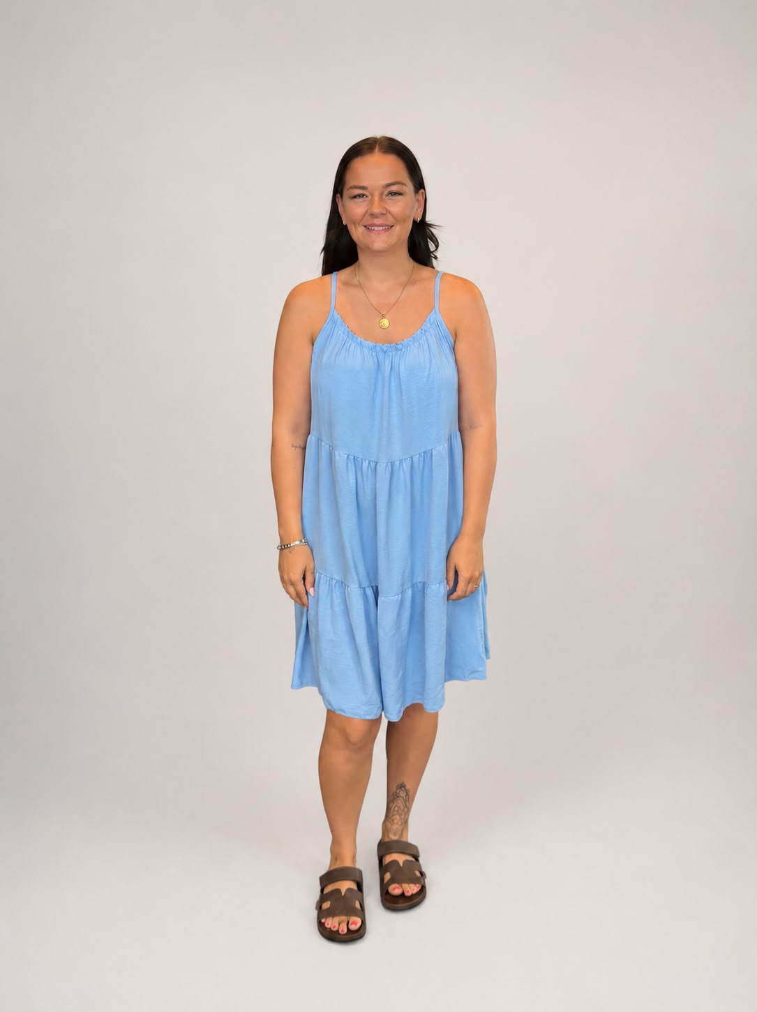 A versatile Light Blue tiered cami dress featuring spaghetti straps, a relaxed, flowy fit, and a flattering knee-length design. Lightweight and easy to wear, it's ideal for casual everyday styling, holidays, weekends, and warm-weather occasions.