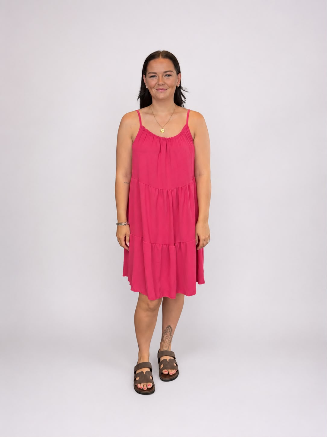 A versatile Pink tiered cami dress featuring spaghetti straps, a relaxed, flowy fit, and a flattering knee-length design. Lightweight and easy to wear, it's ideal for casual everyday styling, holidays, weekends, and warm-weather occasions.