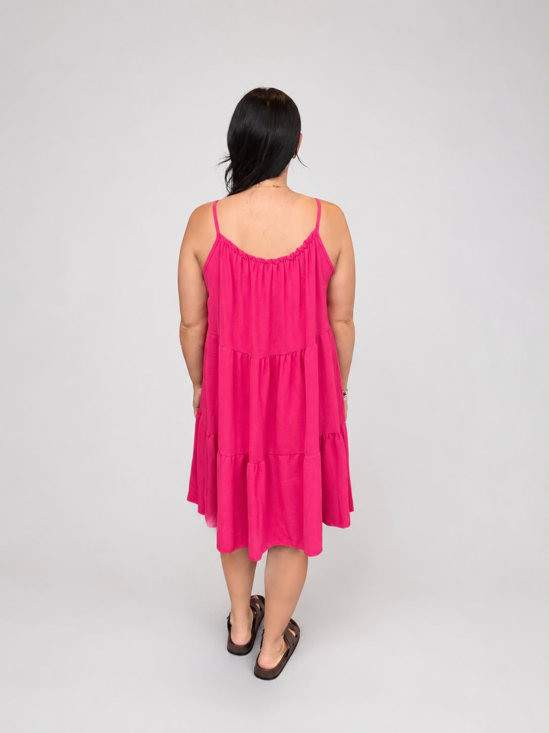 A versatile Pink tiered cami dress featuring spaghetti straps, a relaxed, flowy fit, and a flattering knee-length design. Lightweight and easy to wear, it's ideal for casual everyday styling, holidays, weekends, and warm-weather occasions.