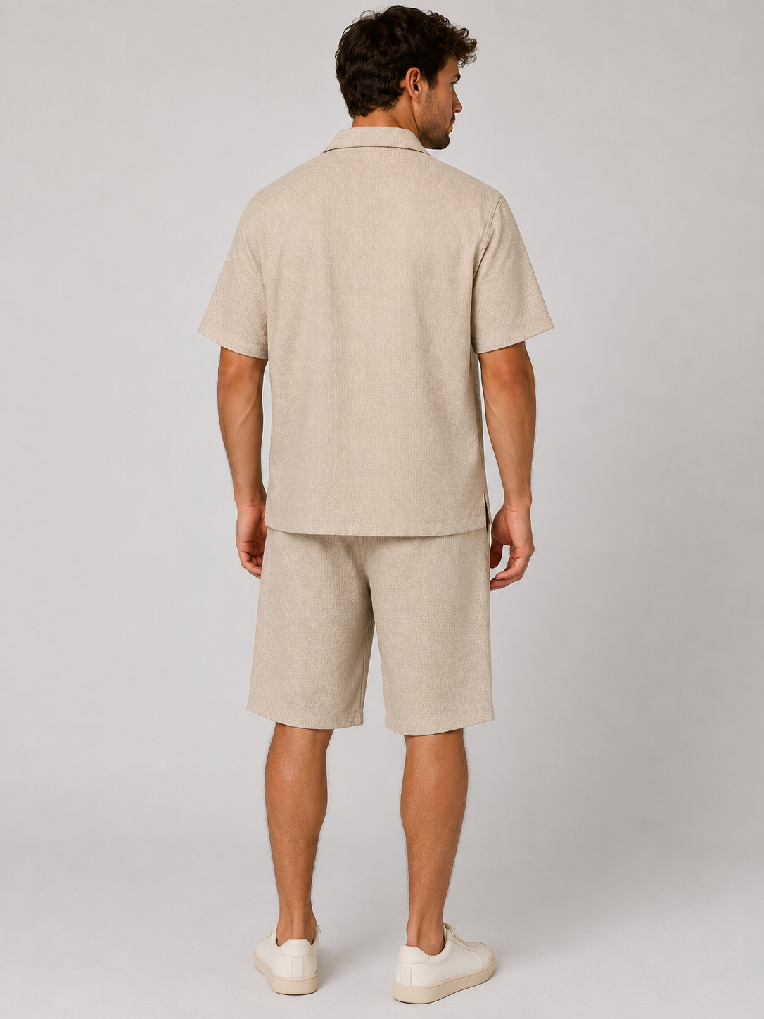 Men’s beige textured shirt and shorts co-ord set with short sleeve button-up shirt, drawstring shorts, and white trainers.