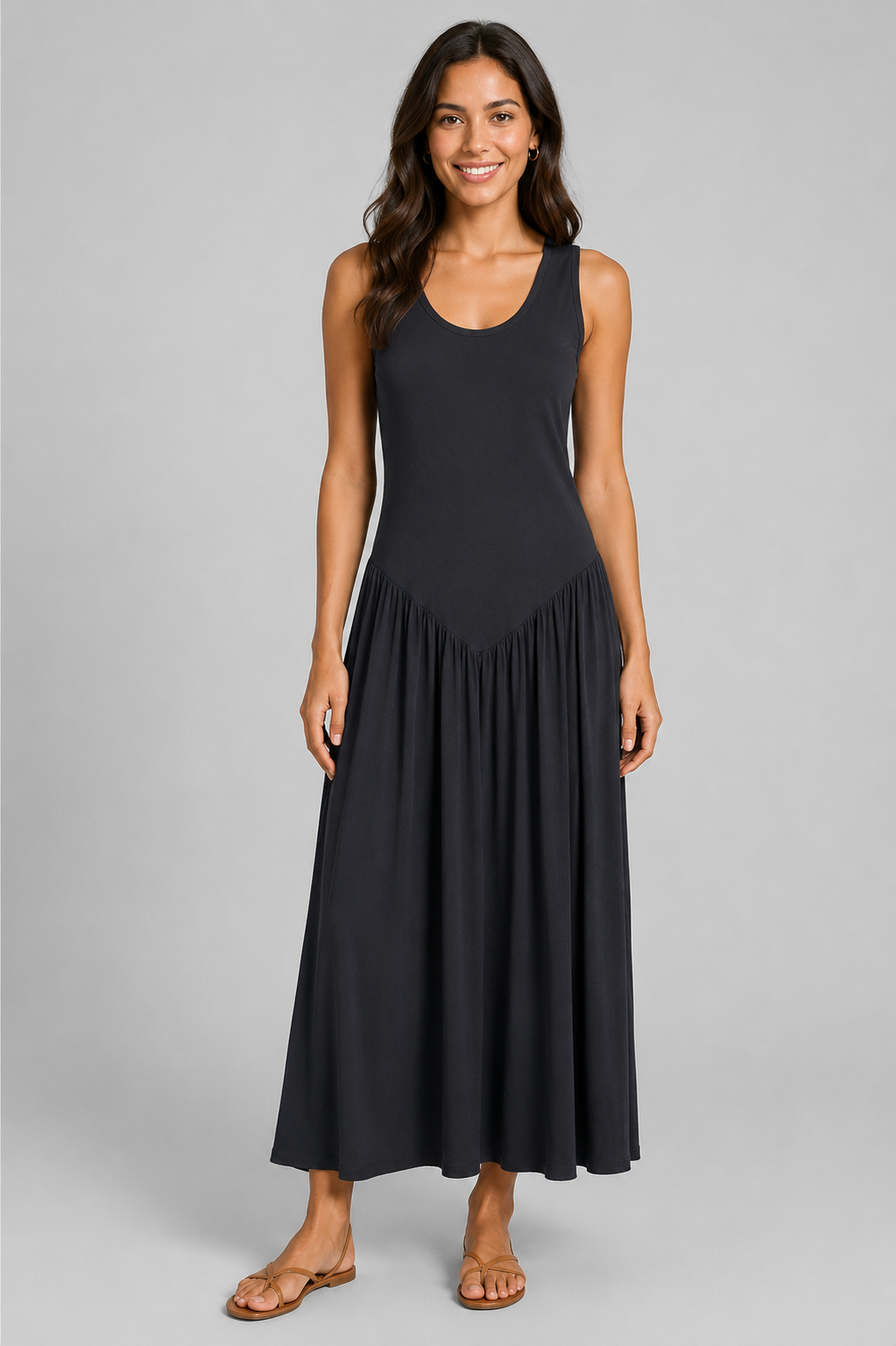 Women's sleeveless maxi dress featuring a scoop neckline, fitted bodice, and flowing gathered skirt. Shown in a soft brown jersey fabric with a relaxed silhouette and maxi length, styled on a model against a light grey studio background.