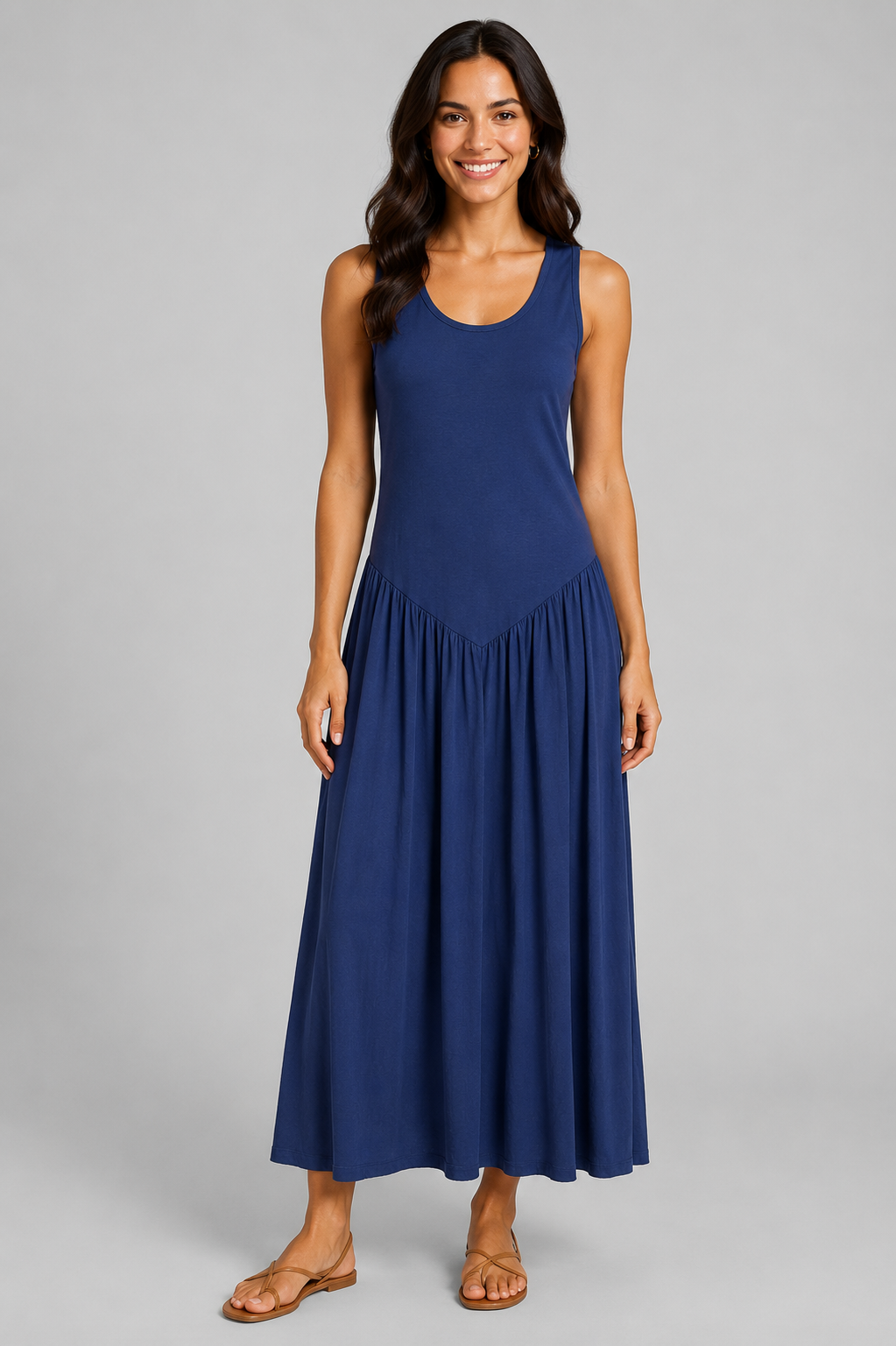 Women's sleeveless maxi dress featuring a scoop neckline, fitted bodice, and flowing gathered skirt. Shown in a soft brown jersey fabric with a relaxed silhouette and maxi length, styled on a model against a light grey studio background.