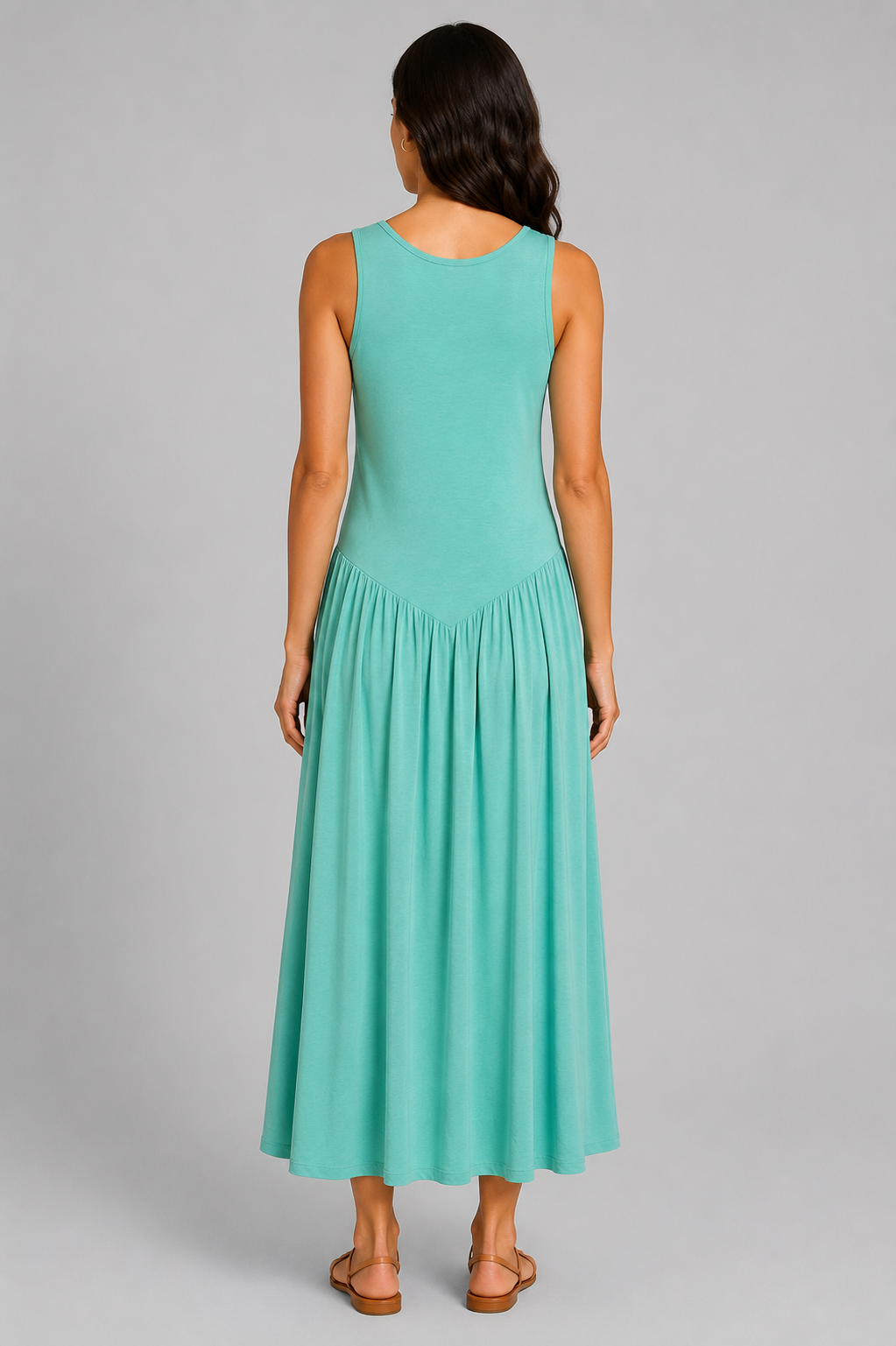 Women's sleeveless maxi dress featuring a scoop neckline, fitted bodice, and flowing gathered skirt. Shown in a soft brown jersey fabric with a relaxed silhouette and maxi length, styled on a model against a light grey studio background.