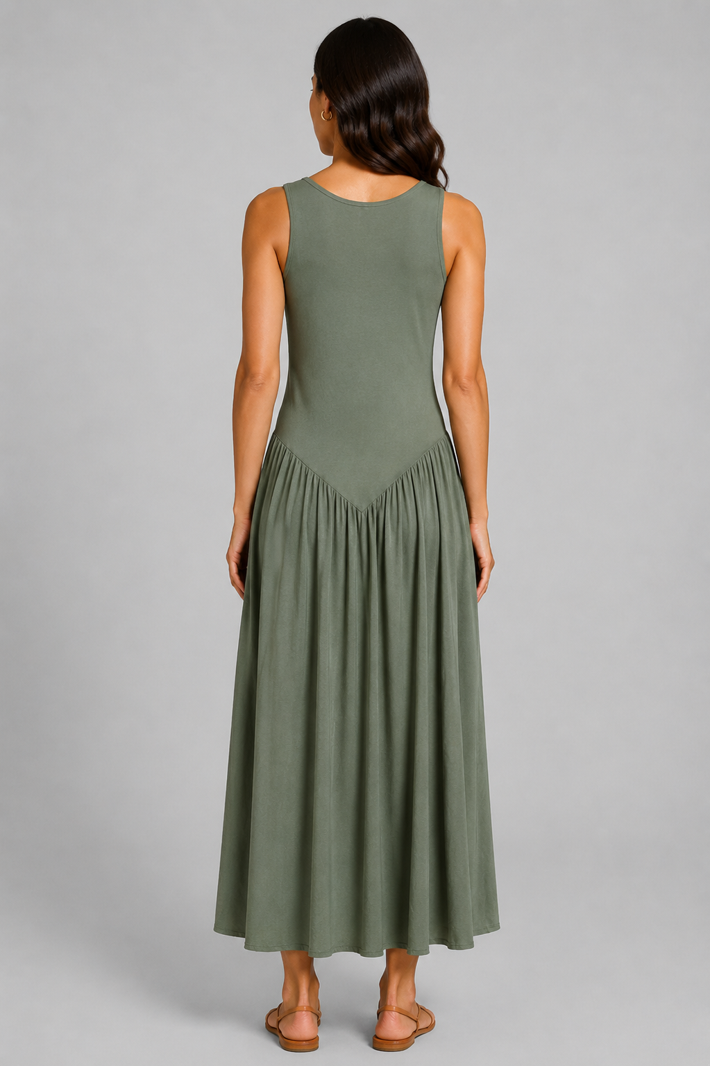 Women's sleeveless maxi dress featuring a scoop neckline, fitted bodice, and flowing gathered skirt. Shown in a soft brown jersey fabric with a relaxed silhouette and maxi length, styled on a model against a light grey studio background.