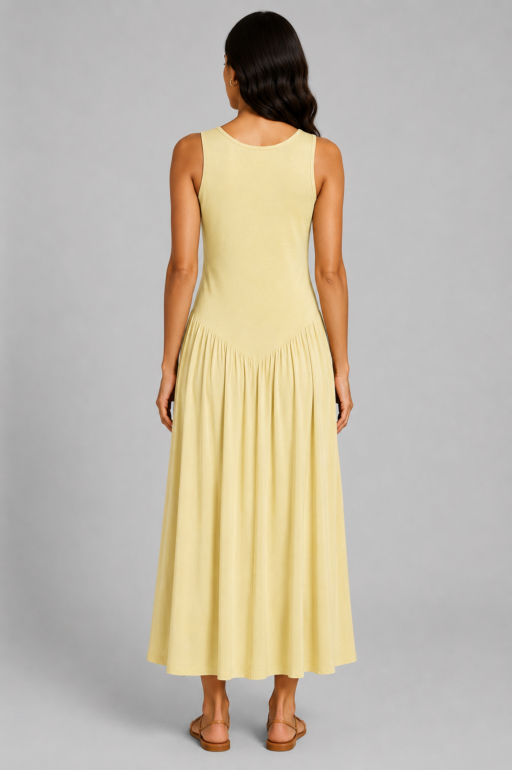 Women's sleeveless maxi dress featuring a scoop neckline, fitted bodice, and flowing gathered skirt. Shown in a soft brown jersey fabric with a relaxed silhouette and maxi length, styled on a model against a light grey studio background.