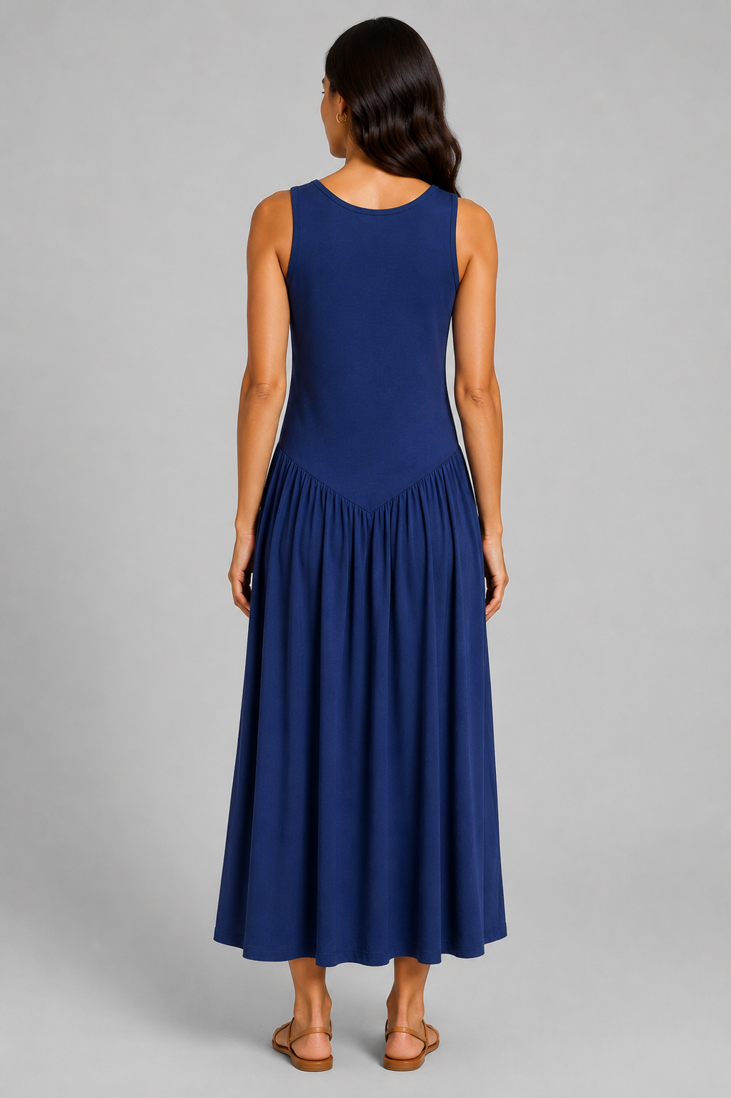 Women's sleeveless maxi dress featuring a scoop neckline, fitted bodice, and flowing gathered skirt. Shown in a soft brown jersey fabric with a relaxed silhouette and maxi length, styled on a model against a light grey studio background.