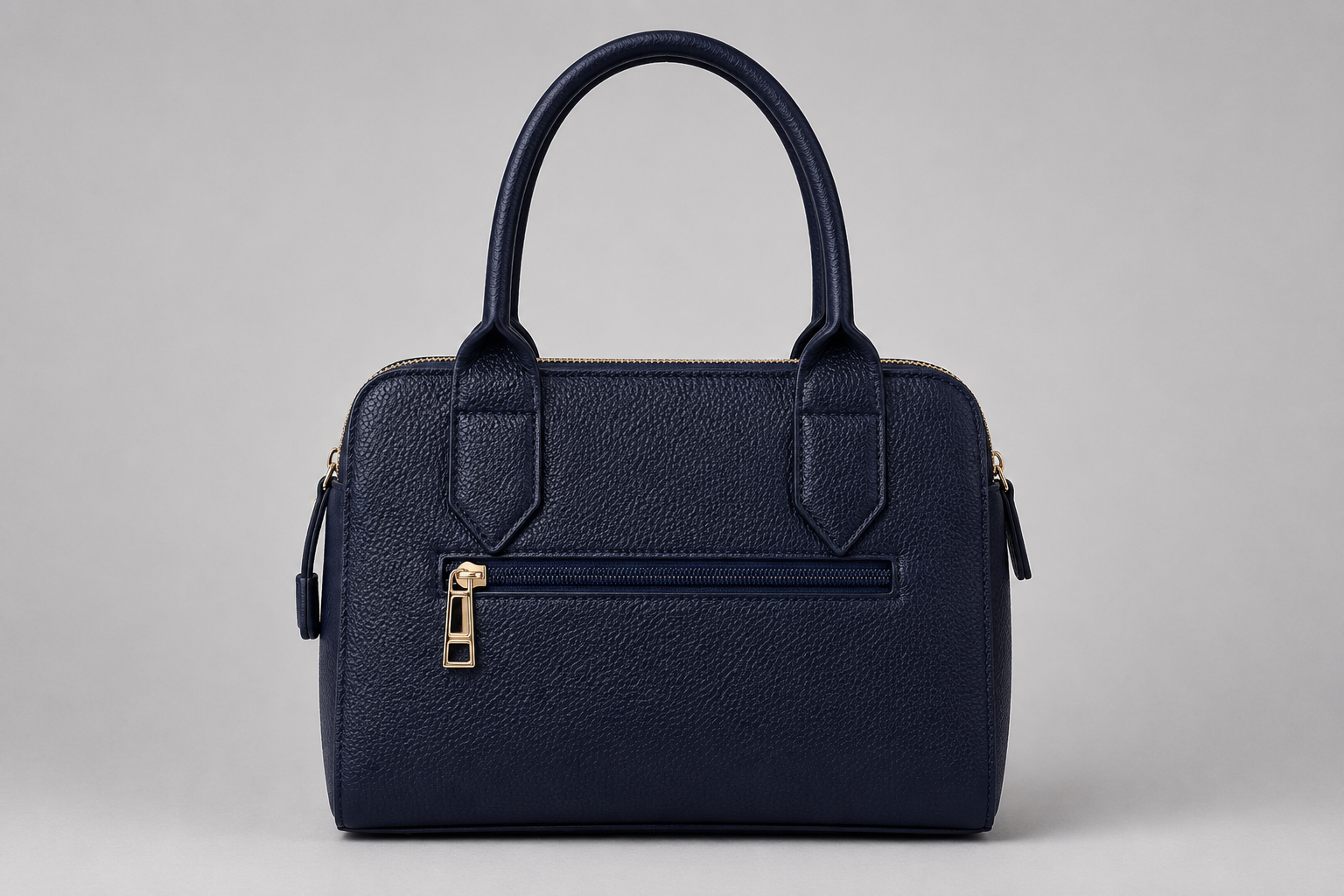 The Chelsea Tote Bag in Navy Blue featuring a structured design, pebbled faux leather finish, double zip compartments, gold-tone hardware, and embossed logo detail on a light grey studio background.