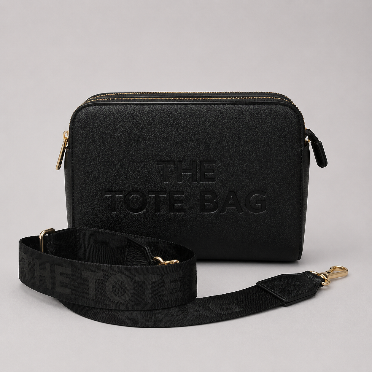 The Tote Bag crossbody bag with adjustable branded strap and gold hardware.