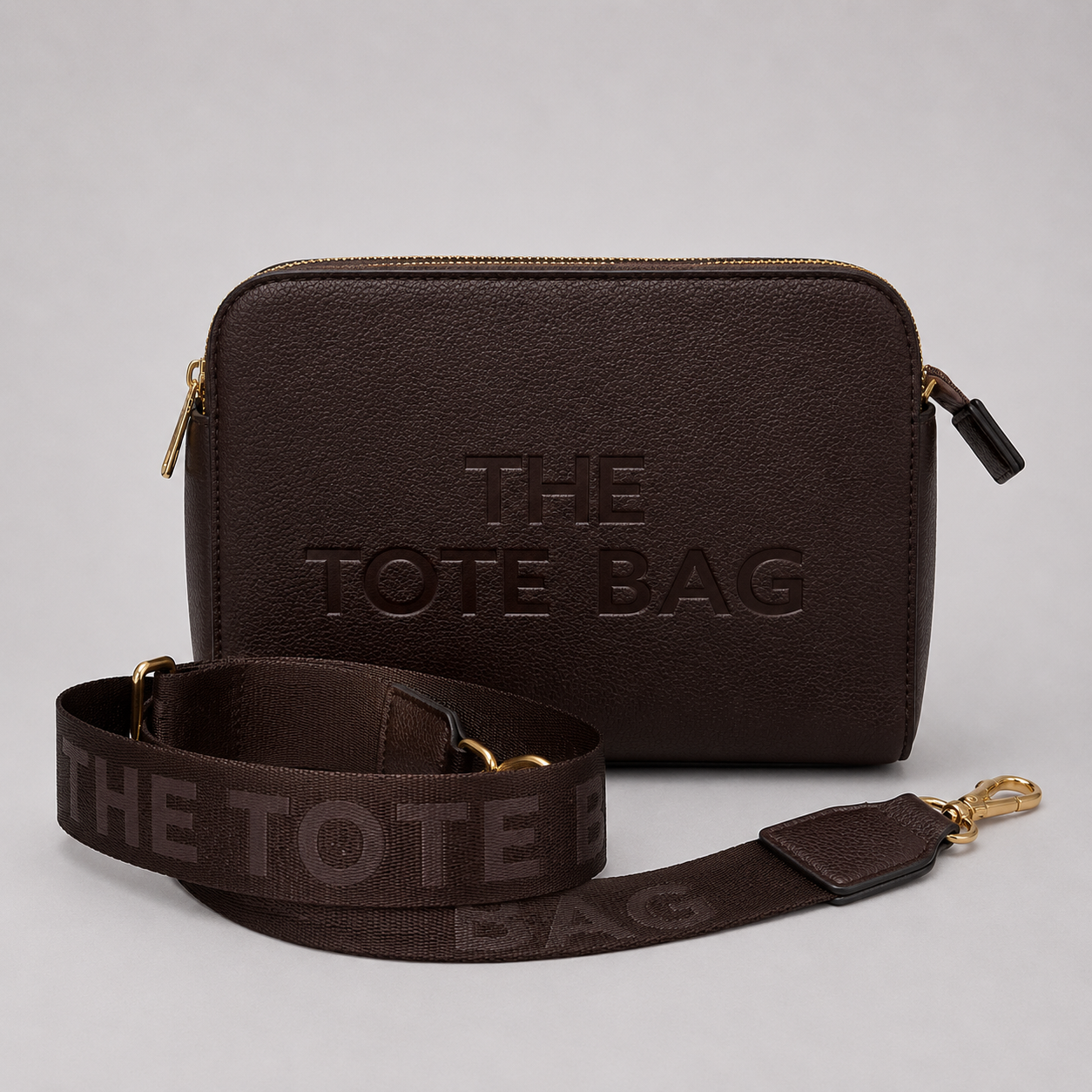 The Tote Bag crossbody bag with adjustable branded strap and gold hardware.
