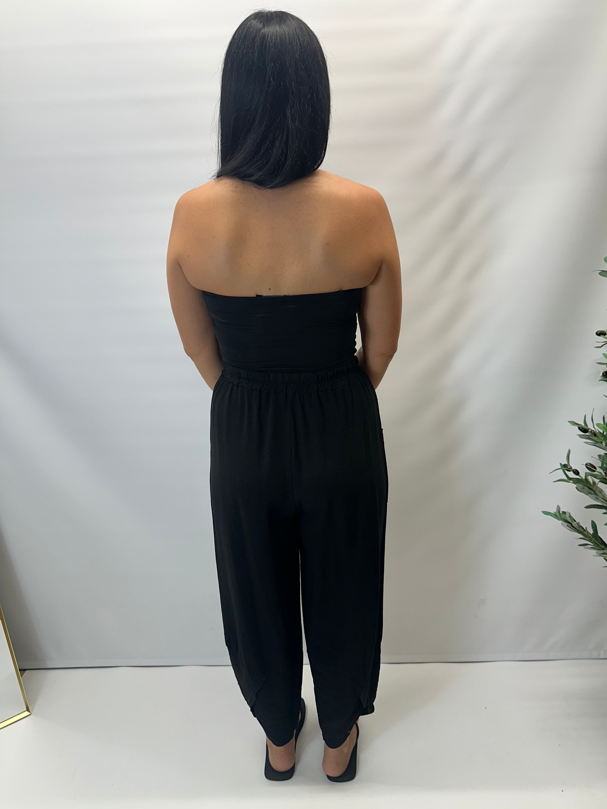 Model wearing black Italian relaxed tapered trousers with an elasticated waistband, front patch pockets and crossover split hem detail.