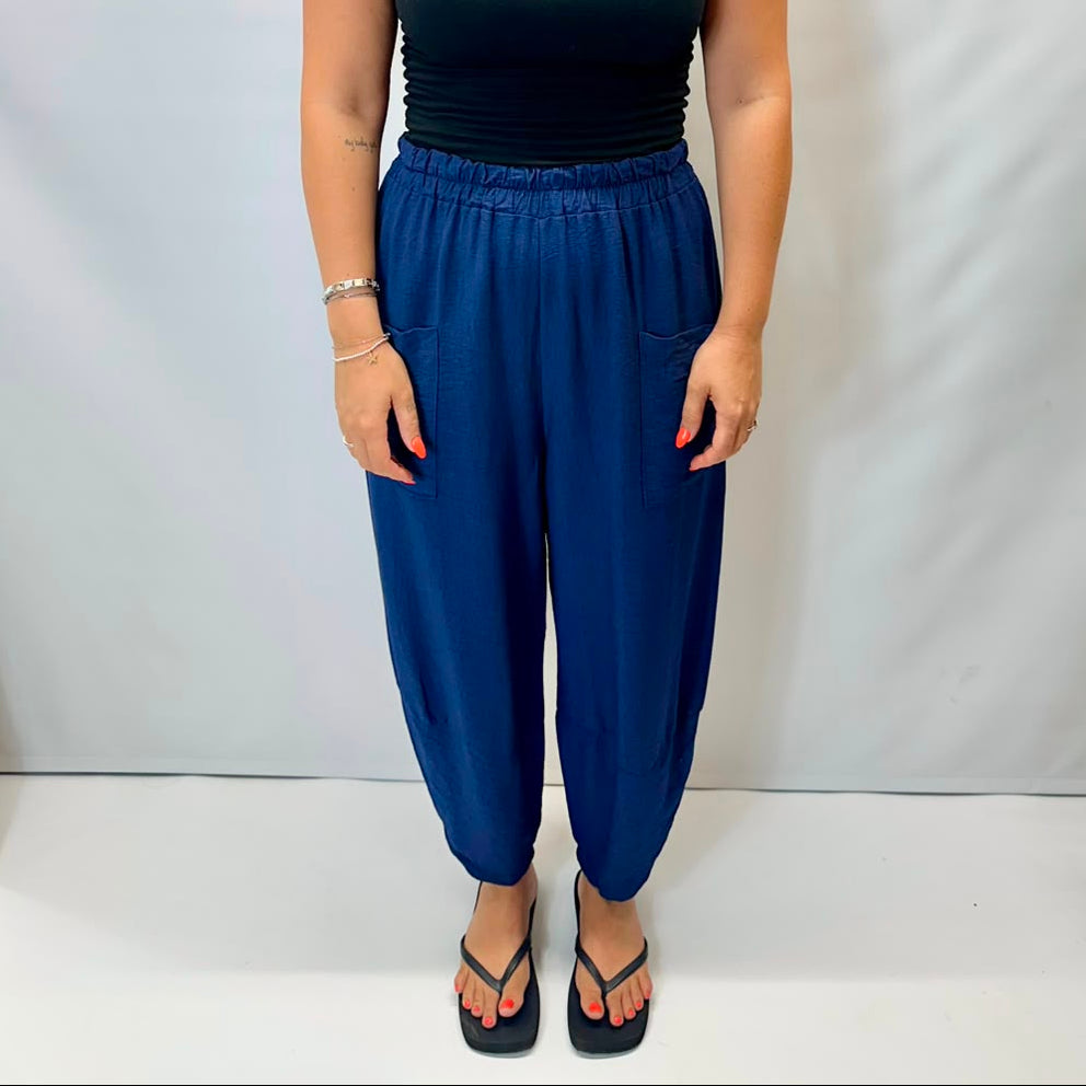 Model wearing navy Italian relaxed tapered trousers with an elasticated waistband, front patch pockets and crossover split hem detail.