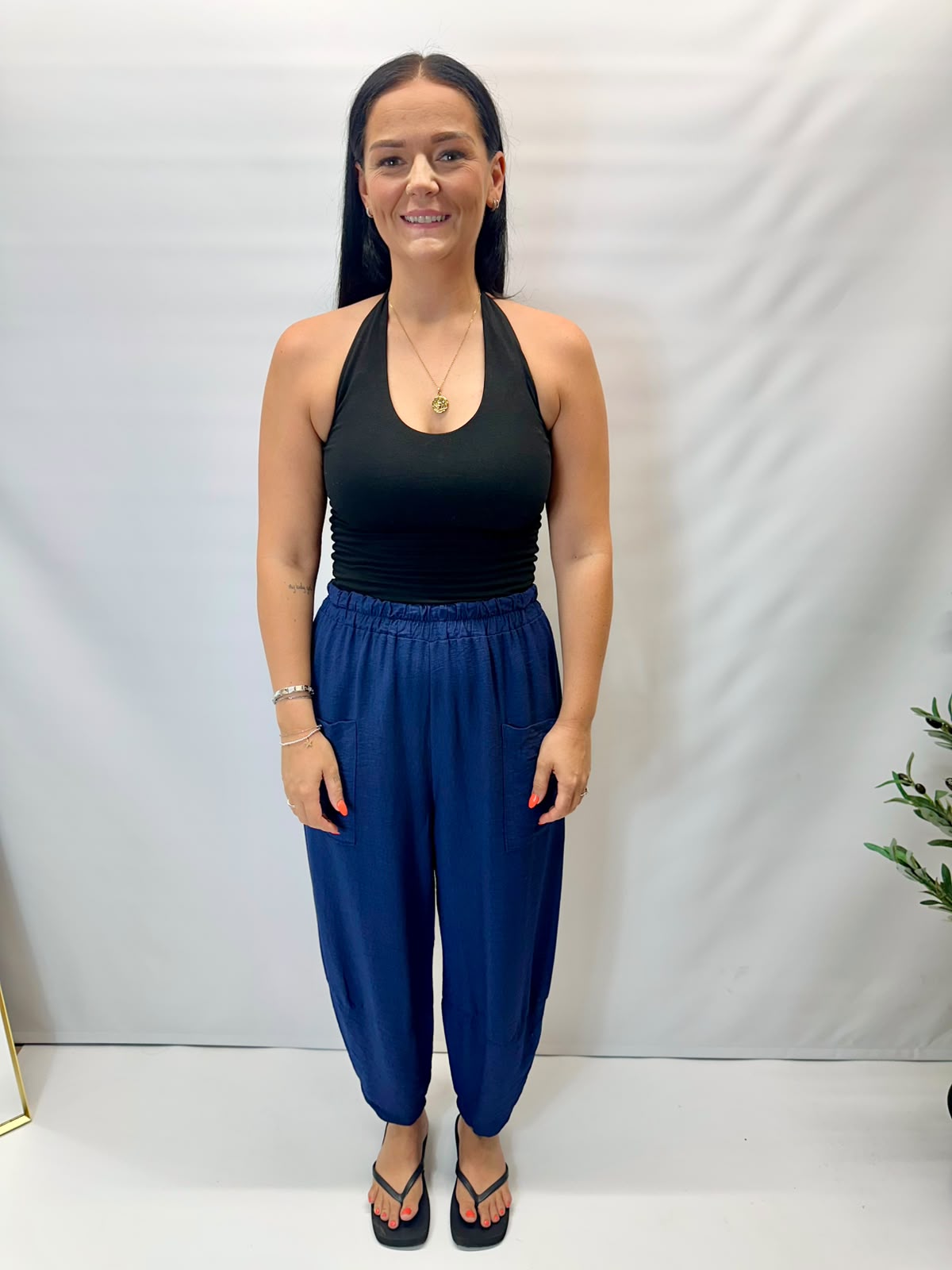 Model wearing navy Italian relaxed tapered trousers with an elasticated waistband, front patch pockets and crossover split hem detail.
