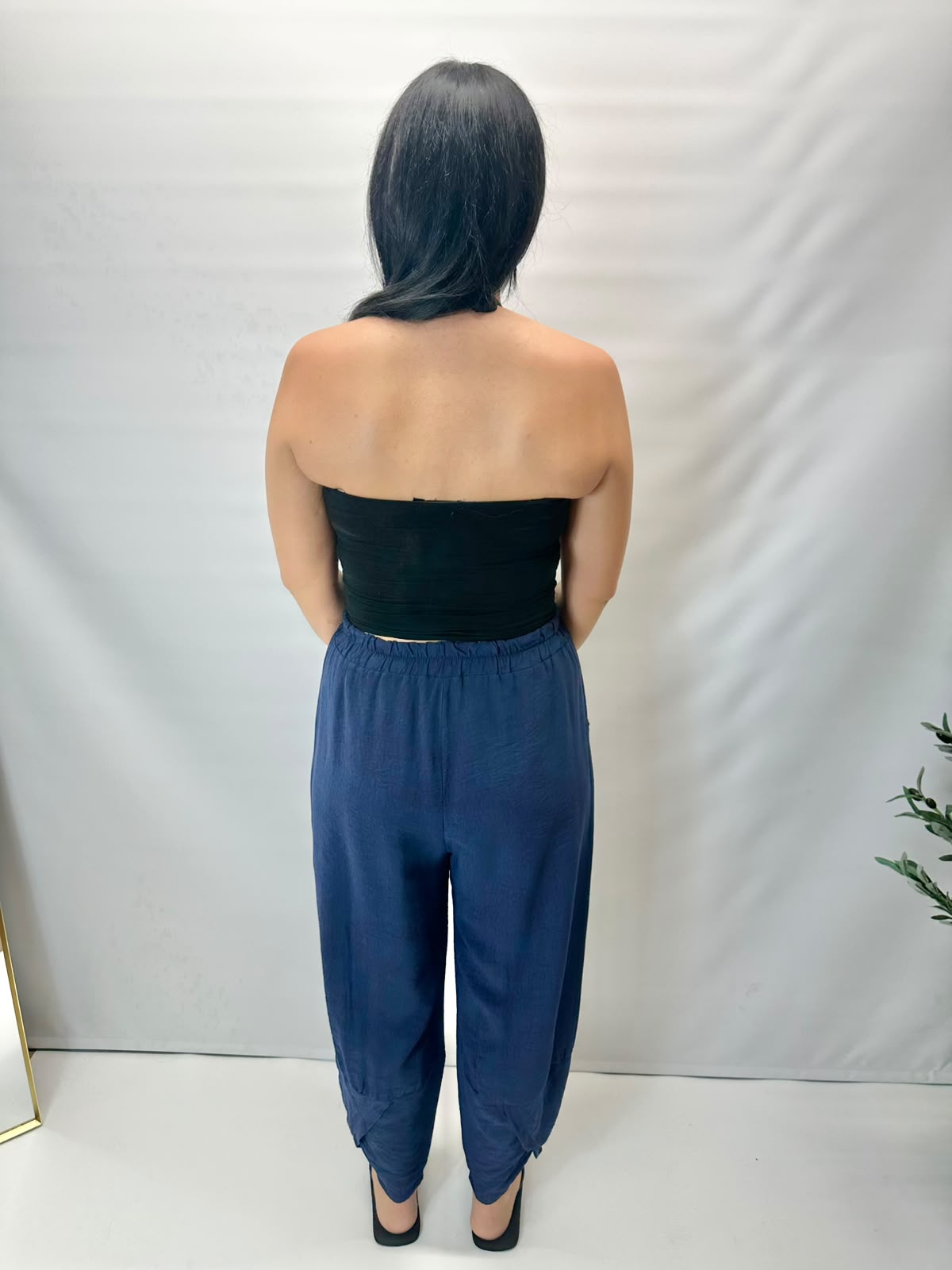 Model wearing navy Italian relaxed tapered trousers with an elasticated waistband, front patch pockets and crossover split hem detail.