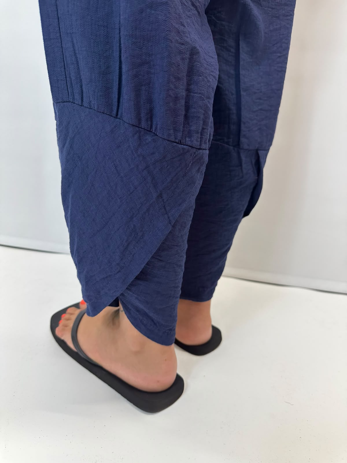 Model wearing navy Italian relaxed tapered trousers with an elasticated waistband, front patch pockets and crossover split hem detail.