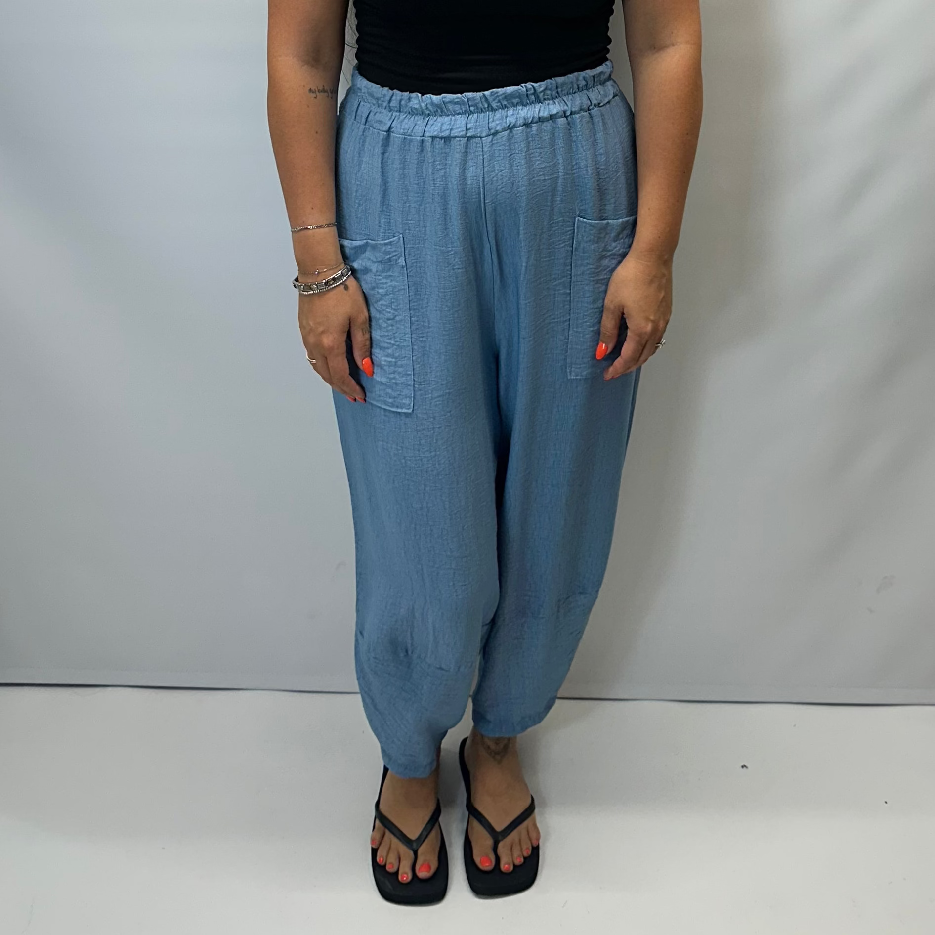 Model wearing Sky Blue Italian relaxed tapered trousers with an elasticated waistband, front patch pockets and crossover split hem detail.