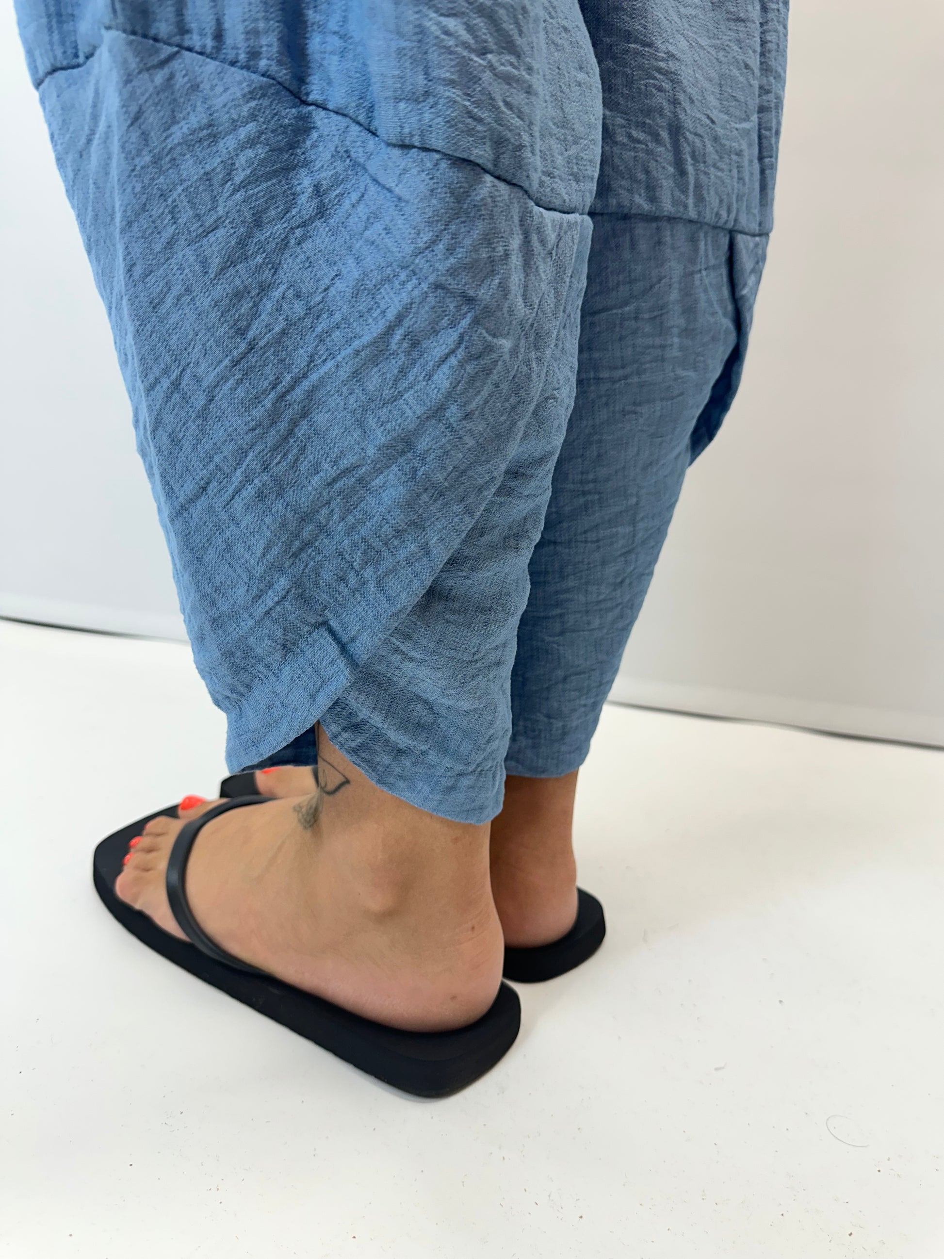 Model wearing black Italian relaxed tapered trousers with an elasticated waistband, front patch pockets and crossover split hem detail.