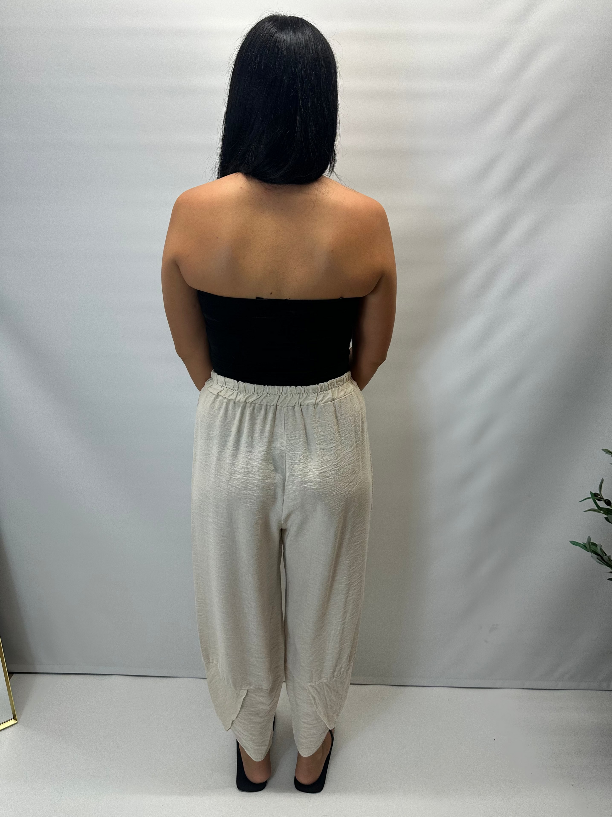 Model wearing beige Italian relaxed tapered trousers with an elasticated waistband, front patch pockets and crossover split hem detail.