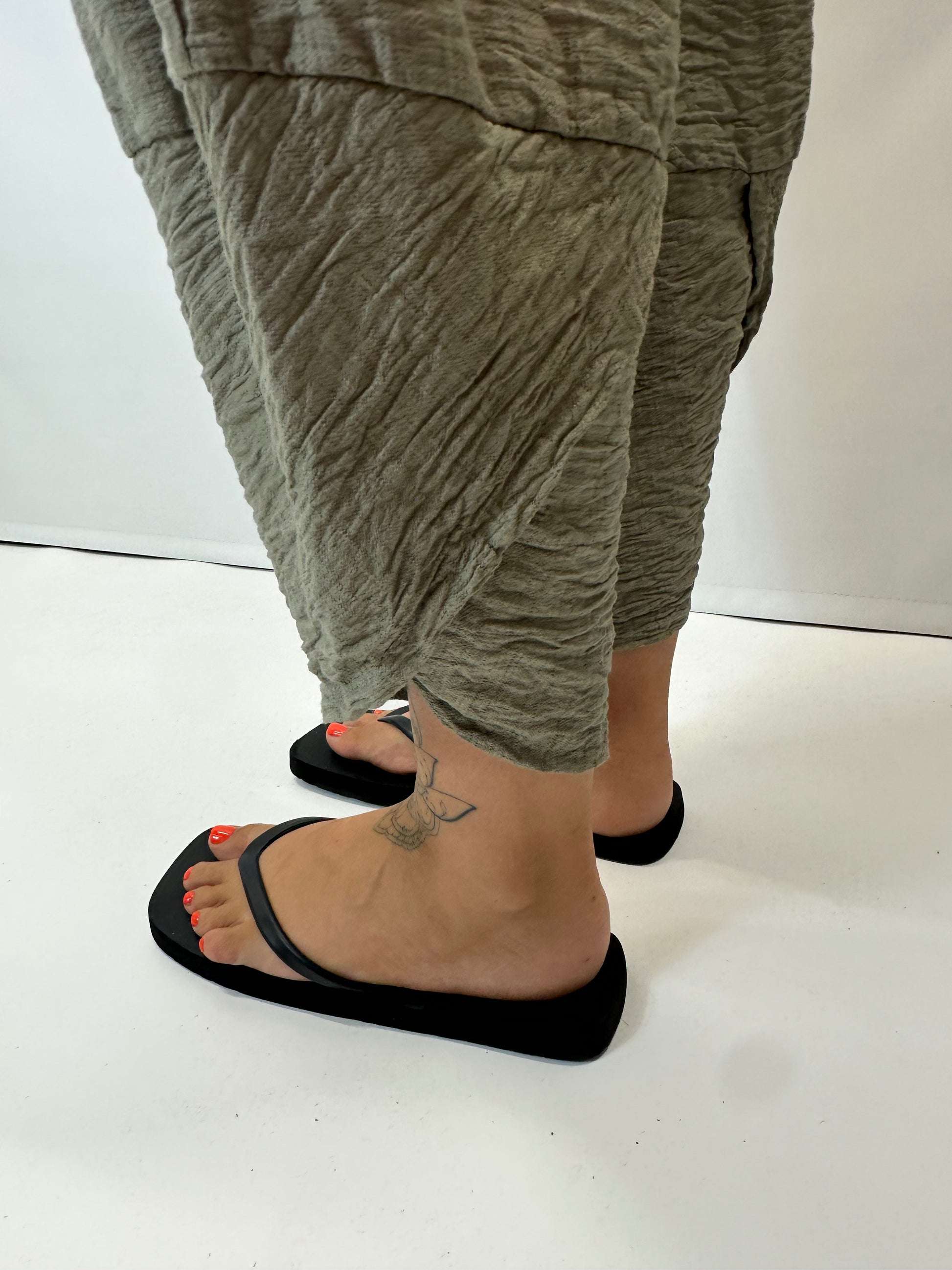 Model wearing khaki Italian relaxed tapered trousers with an elasticated waistband, front patch pockets and crossover split hem detail.