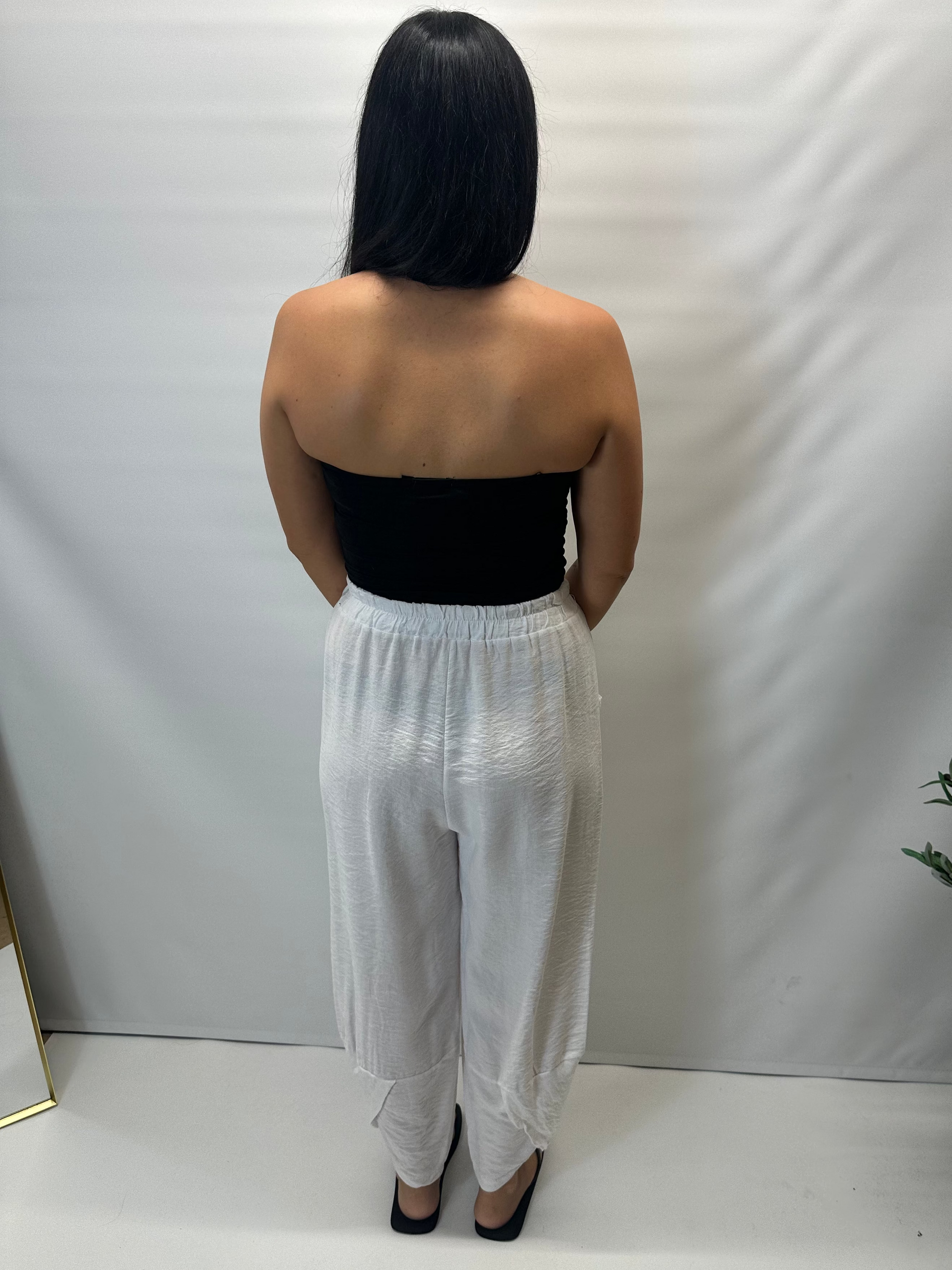 Model wearing white Italian relaxed tapered trousers with an elasticated waistband, front patch pockets and crossover split hem detail.