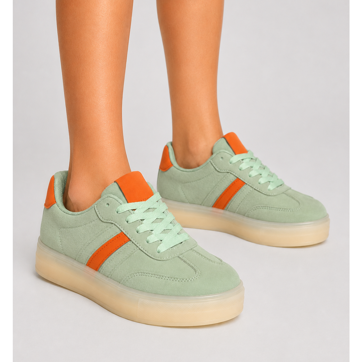 Mint green platform trainers featuring orange contrast accents, smooth synthetic upper and chunky translucent sole for everyday wear.